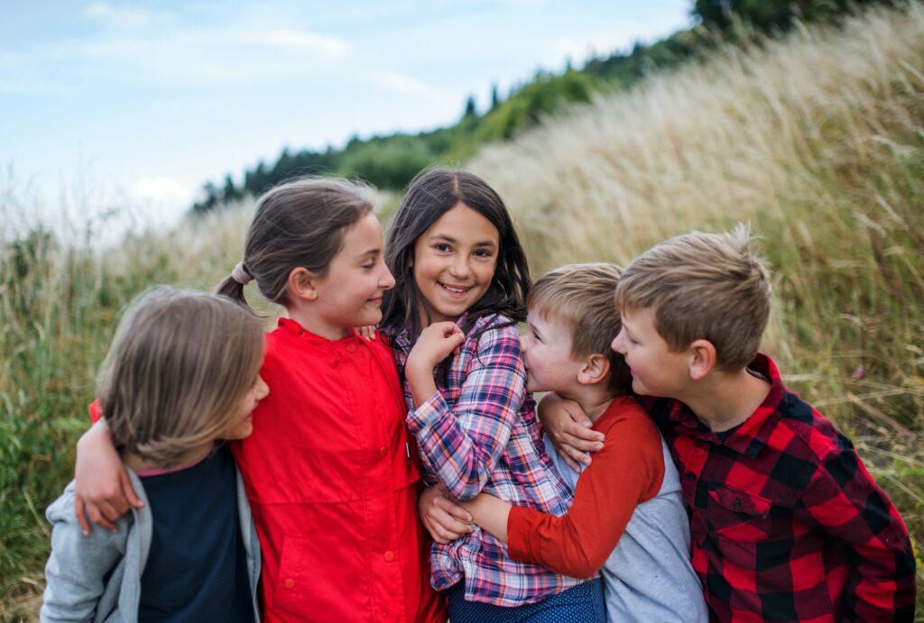 Group of school children standing on field trip in nature, playing.